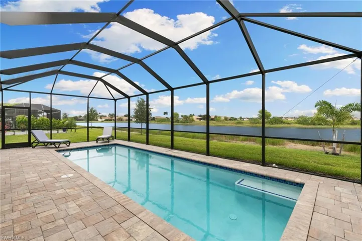 Swimming pool with a lawn, a sunroom, a water view, and a lanai