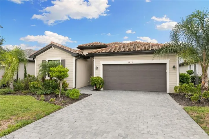 View of front of home featuring a tile roof, an attached garage, and decorative driveway