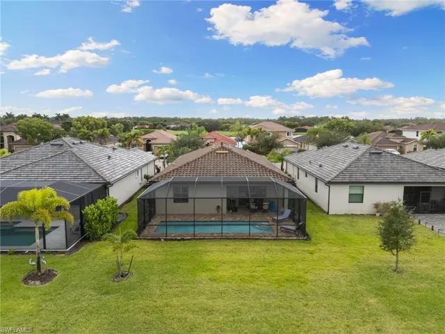 Swimming pool with a residential view, a sunroom, a lanai, and a yard