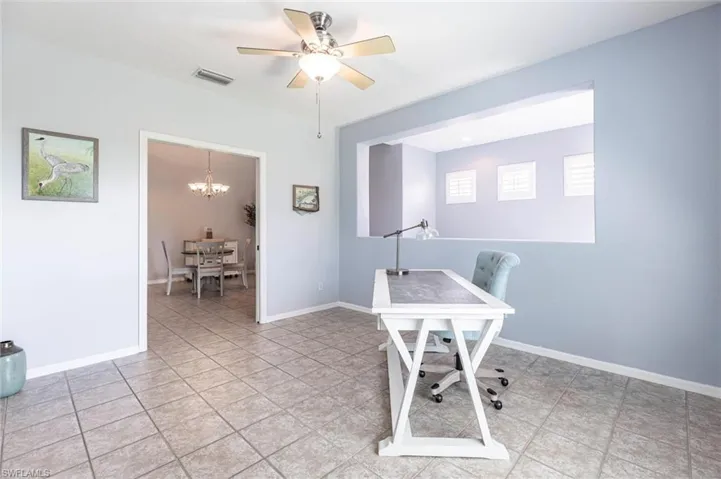 Office area with a chandelier, a ceiling fan, and light tile patterned flooring