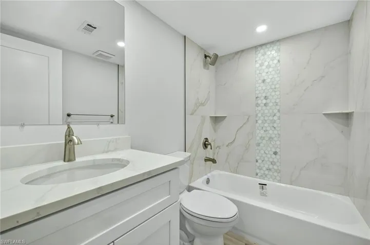 Bathroom featuring washtub / shower combination, vanity, and recessed lighting