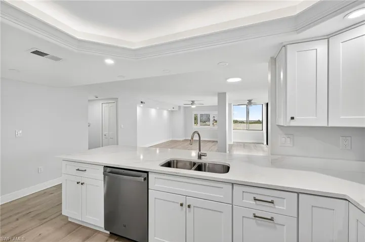 Kitchen with light plank stile  floors, recessed lighting, white cabinetry, dishwasher, and light stone counters