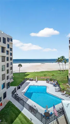 Community pool featuring a patio area and view of water and beach