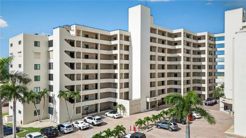 View of condo building / complex featuring uncovered parking