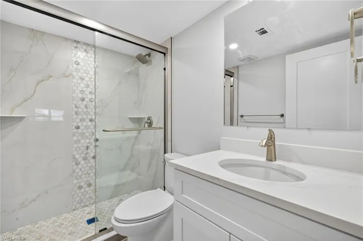 Bathroom featuring a marble finish shower and vanity