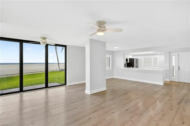 Unfurnished living room with a water view, light plank tile flooring, ceiling fan, and a wall of windows