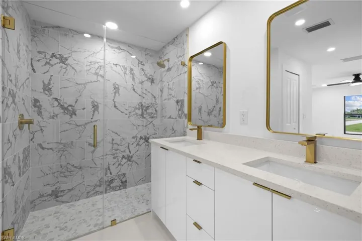 Bathroom with a marble finish shower, recessed lighting, double vanity, and a ceiling fan