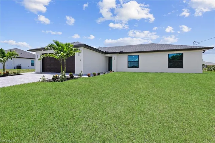 View of front of house featuring decorative driveway, an attached garage, stucco siding, and a front yard