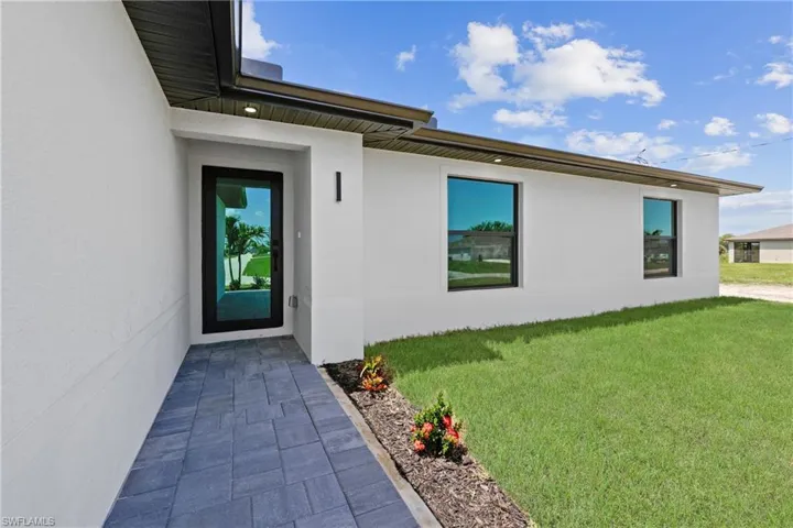 Entrance to property with stucco siding and a yard