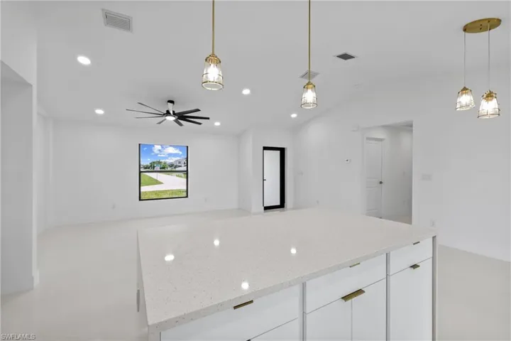 Kitchen with white cabinets, recessed lighting, decorative light fixtures, a kitchen island, and light stone countertops
