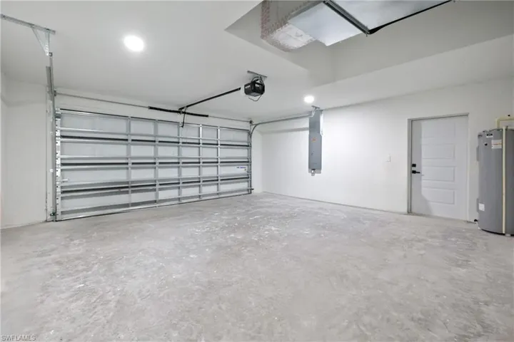 Garage with water heater, recessed lighting, electric panel, and a garage door opener