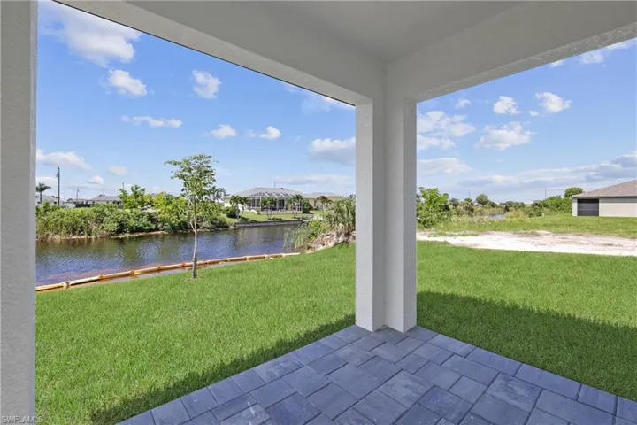 View of green lawn featuring a water view and a patio area