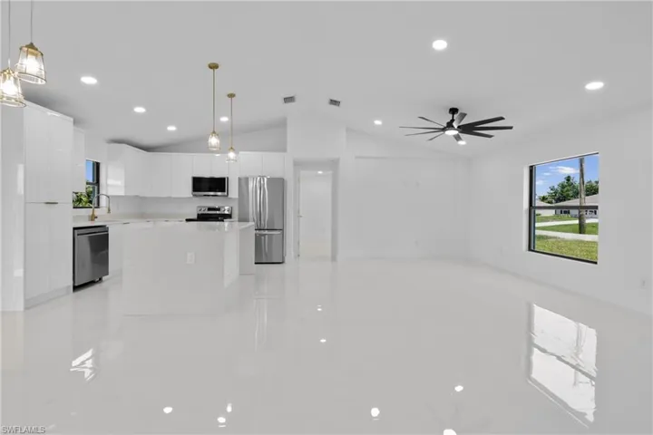 Kitchen featuring a center island, white cabinets, stainless steel appliances, modern cabinets, and vaulted ceiling