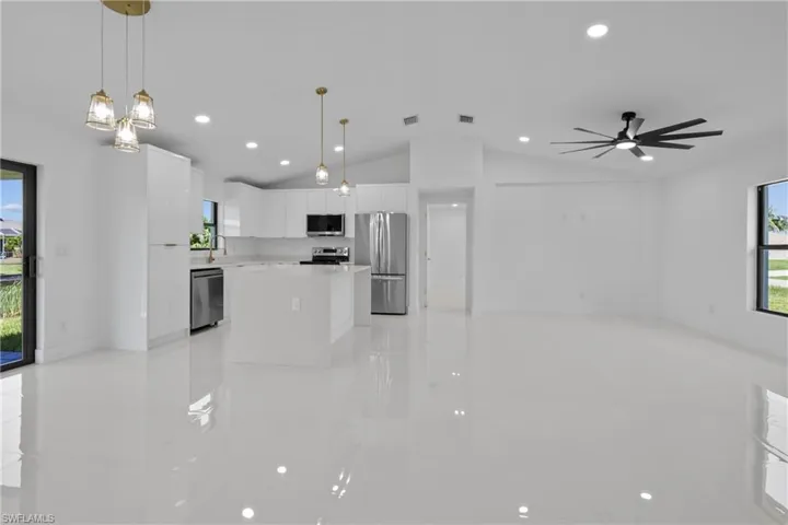 Kitchen with light tile patterned floors, healthy amount of natural light, vaulted ceiling, appliances with stainless steel finishes, and recessed lighting