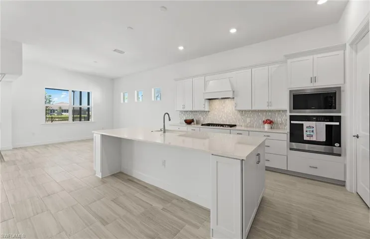 Kitchen with oven, a kitchen island with sink, gas stovetop, sink, and built in microwave