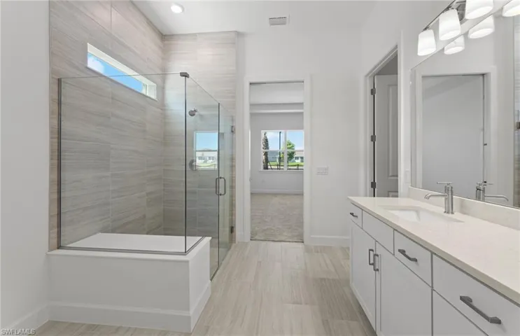Bathroom with tile floors, a shower with door, and vanity