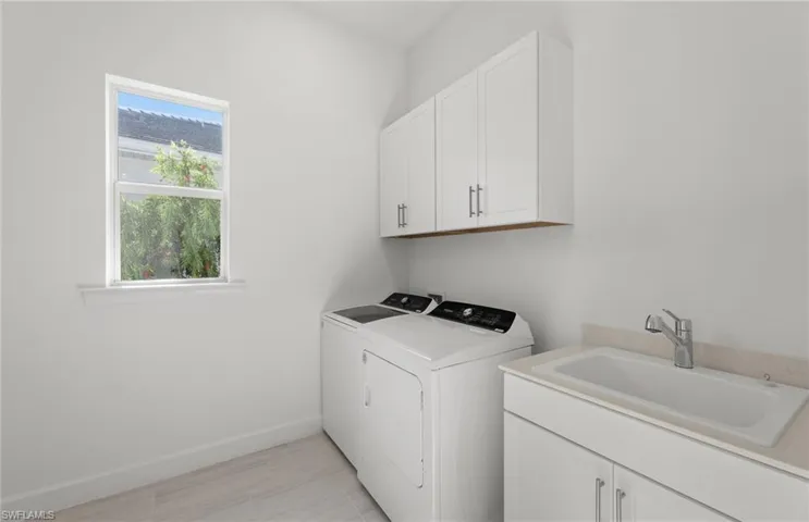 Laundry room featuring plenty of natural light, sink, washer and dryer, and cabinets
