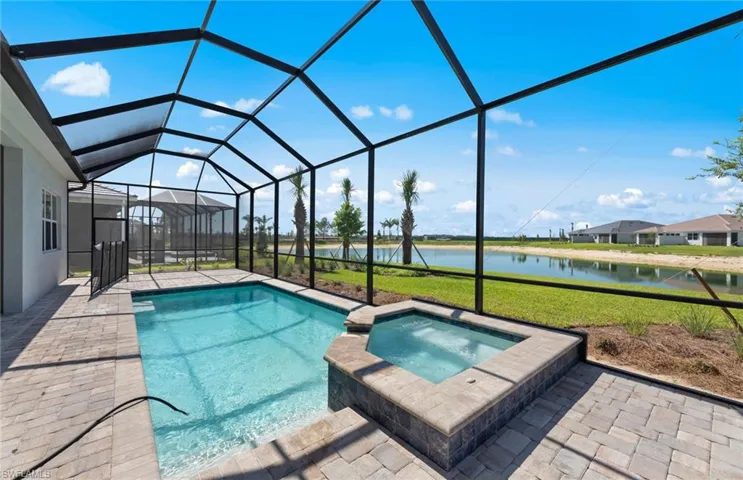 View of swimming pool featuring a water view, glass enclosure, an in ground hot tub, a patio area, and a yard