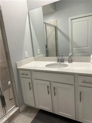 Bathroom with vanity, walk in shower, and tile patterned flooring