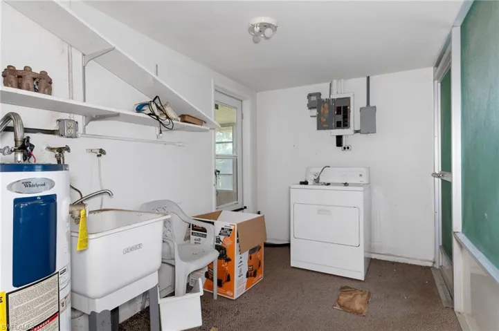 Laundry room with electric panel, dark carpet, water heater, sink, and washer / clothes dryer