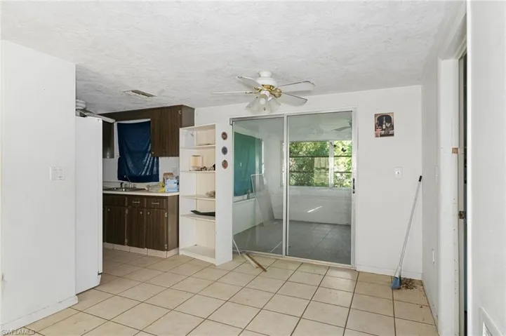 Kitchen with ceiling fan, light tile patterned flooring, sink, dark brown cabinets, and a textured ceiling