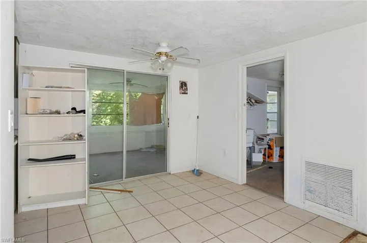 Tiled empty room with ceiling fan and a textured ceiling