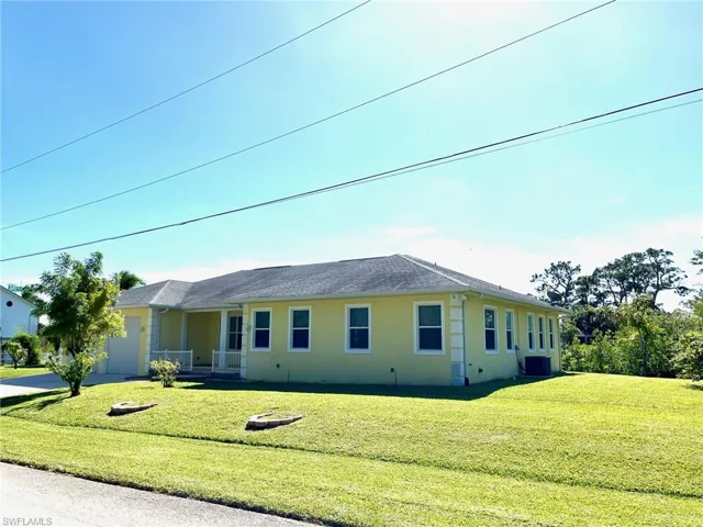 View of front of property featuring a front lawn and central AC