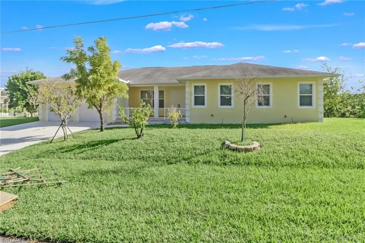 Elevated, one story home with tiled front porch, double front doors, front lawn and XL garage