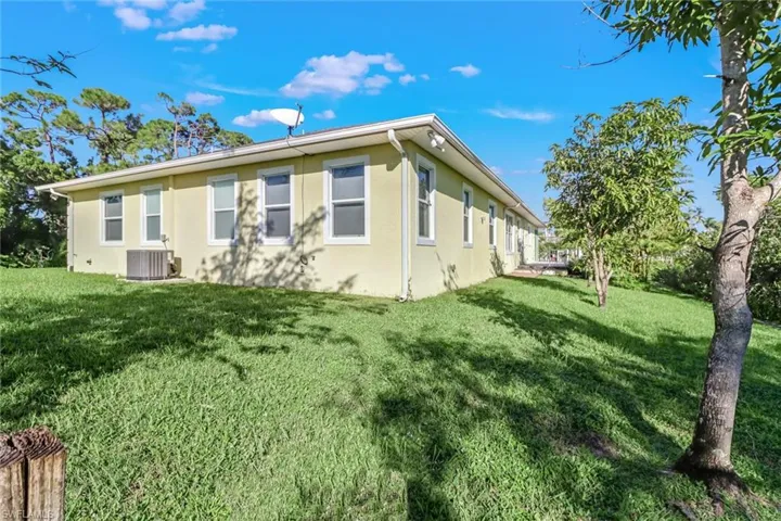 View of side of property featuring a yard and central AC unit