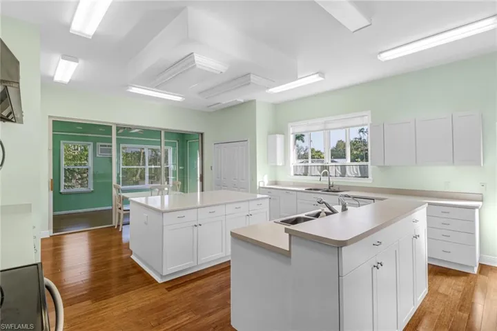Kitchen with white cabinetry, sink, wood-type flooring, and a kitchen island