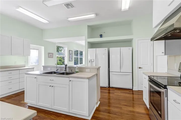 Kitchen featuring ventilation hood, white cabinetry, white fridge, and electric range