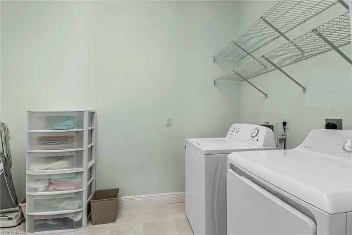 Laundry room with light tile patterned flooring and washer and clothes dryer