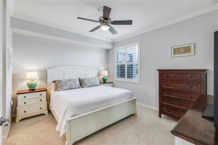 Carpeted bedroom with ceiling fan and ornamental molding