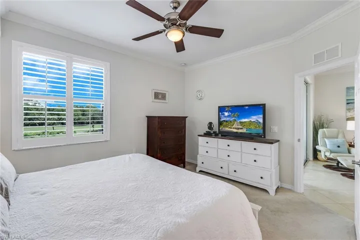 Carpeted bedroom featuring ceiling fan and ornamental molding