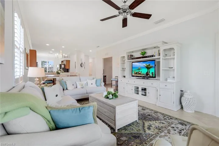 Tiled living room featuring ceiling fan with notable chandelier and ornamental molding