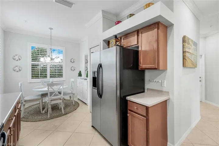 Kitchen featuring decorative light fixtures, an inviting chandelier, crown molding, stainless steel fridge with ice dispenser, and light tile patterned flooring