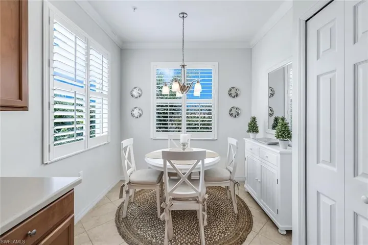 Dining area featuring a notable chandelier, ornamental molding, and light tile patterned floors