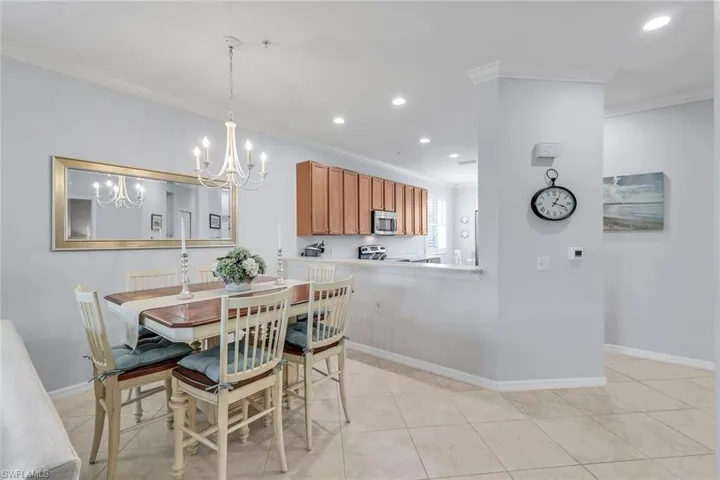 Tiled dining room with an inviting chandelier and ornamental molding