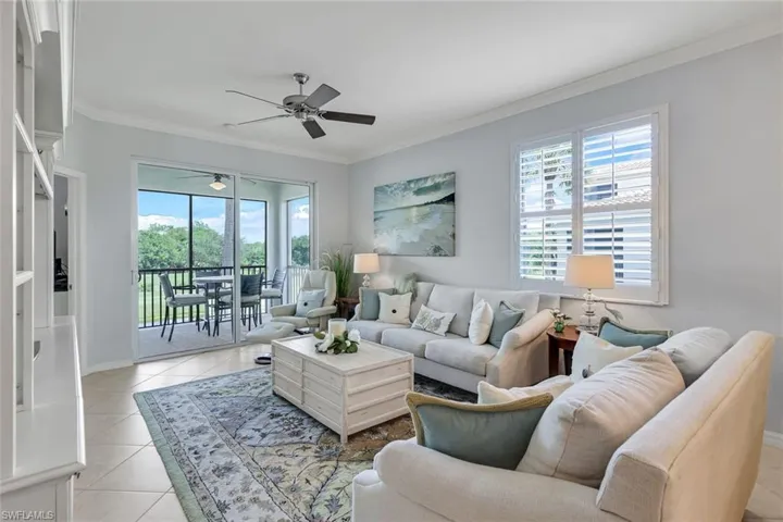 Living room featuring ceiling fan, light tile patterned flooring, and crown molding