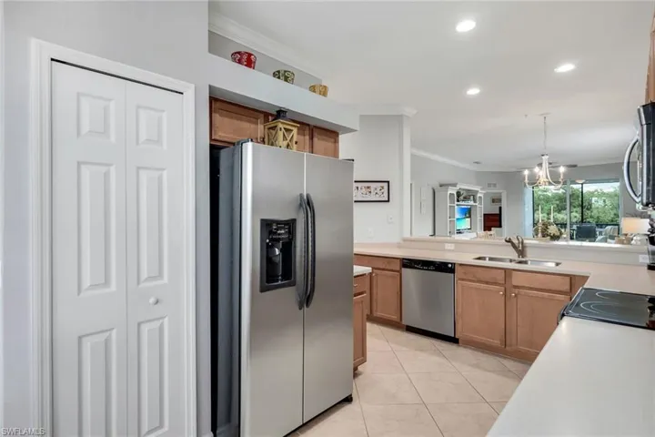 Kitchen featuring light tile patterned floors, appliances with stainless steel finishes, sink, and crown molding