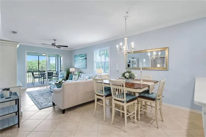 Dining area featuring light tile patterned floors, ceiling fan with notable chandelier, and crown molding