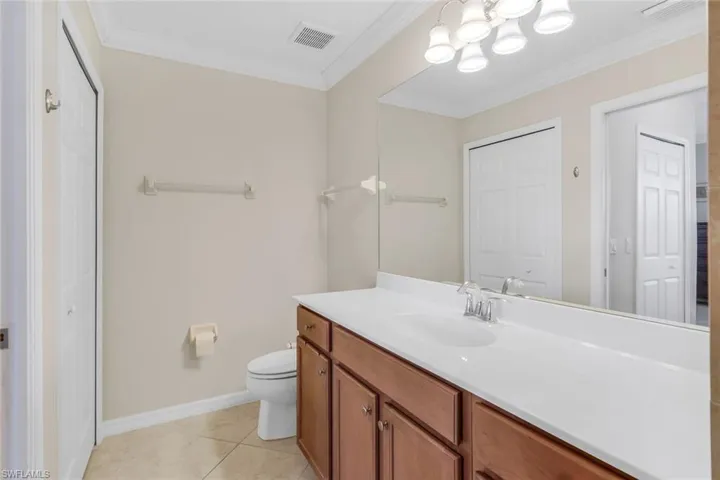 Bathroom featuring tile patterned flooring, vanity, ornamental molding, and toilet
