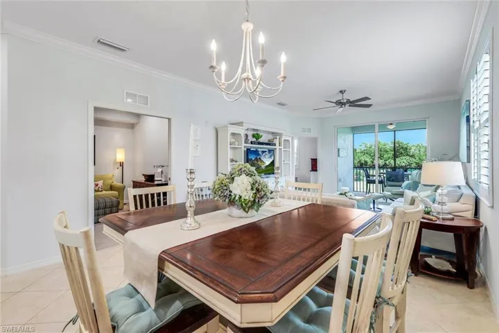 Tiled dining room featuring ceiling fan with notable chandelier and ornamental molding