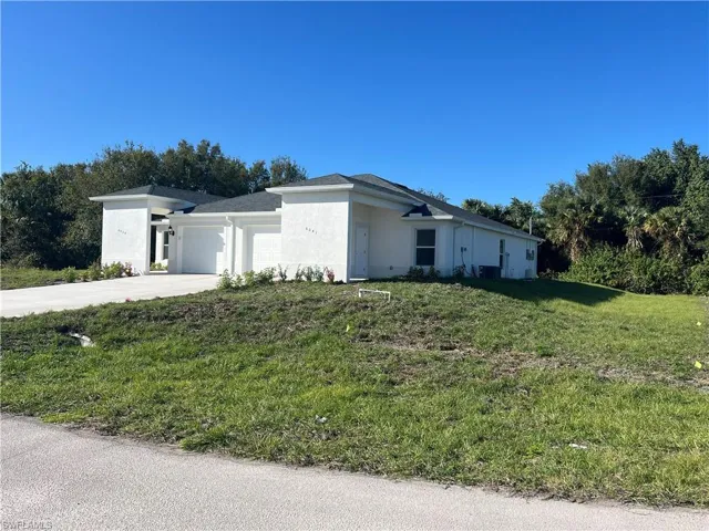 View of front facade featuring a garage and a front lawn