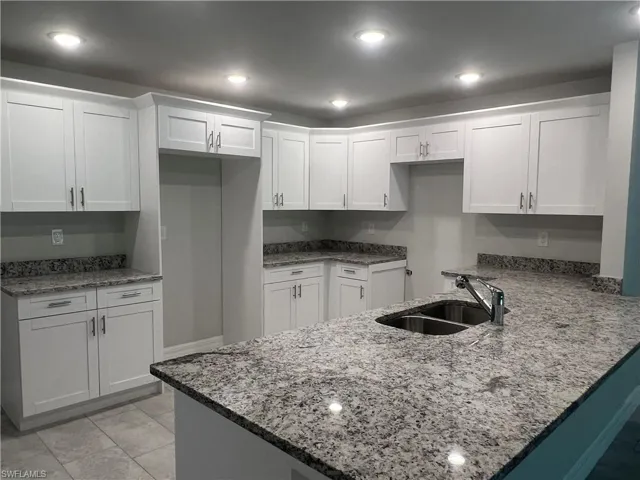 Kitchen with kitchen peninsula and white cabinetry