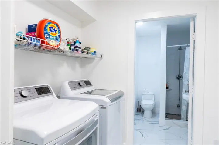 Laundry area featuring light marble finish floors and washing machine and clothes dryer