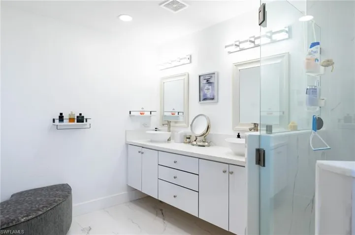 Full bathroom with double vanity, a marble finish shower, light marble finish flooring, and recessed lighting