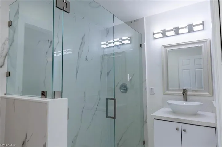 Full bathroom featuring vanity and a marble finish shower