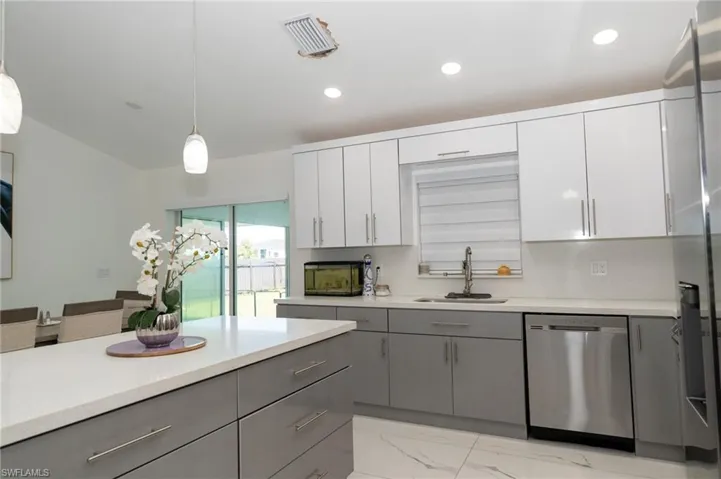 Kitchen featuring gray cabinets, hanging light fixtures, appliances with stainless steel finishes, white cabinets, and recessed lighting
