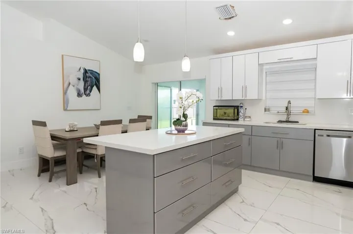 Kitchen with gray cabinetry, dishwasher, a center island, pendant lighting, and light marble finish flooring